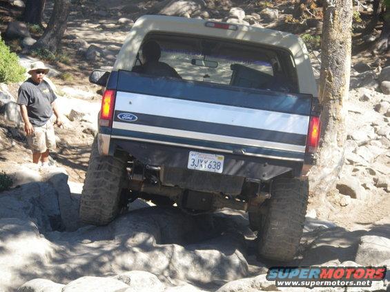 Dark blue and tan Ford Bronco on rocky terrain, rear view