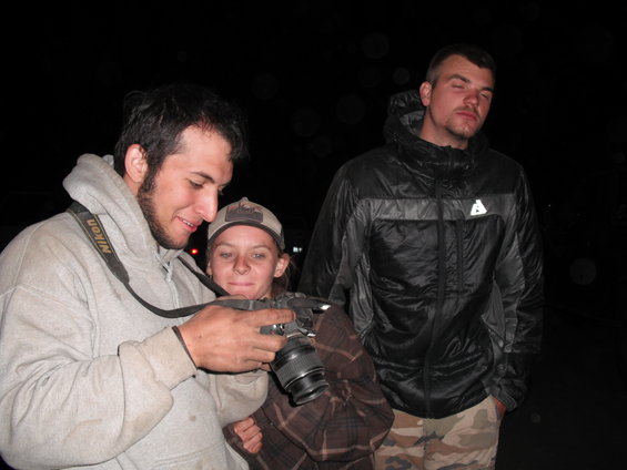 Three people gathered around a camera in the dark