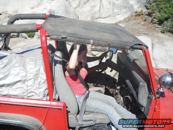 Red off-road vehicle interior with woman driving, seatbelts fastened