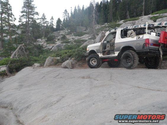 1991 Ford Bronco off-road with doors removed, parked on rocky terrain