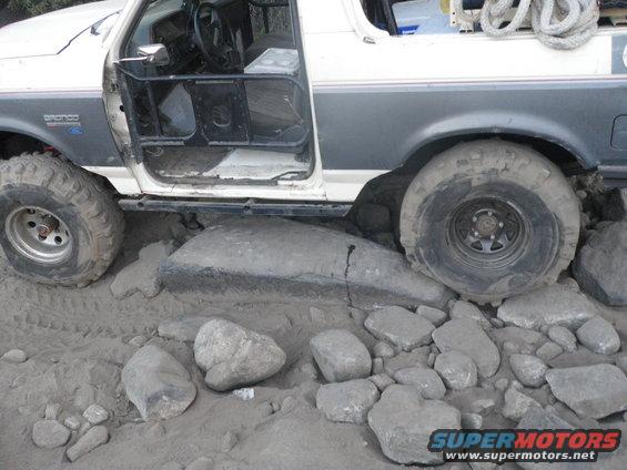 1991 Ford Bronco with door open, tires on rocks and sand