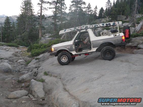 White and grey 1991 Ford Bronco off-roading with a canoe on the roof