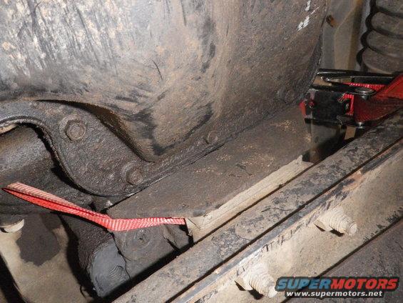 Close-up of vehicle undercarriage with red strap and Supermotors.net logo