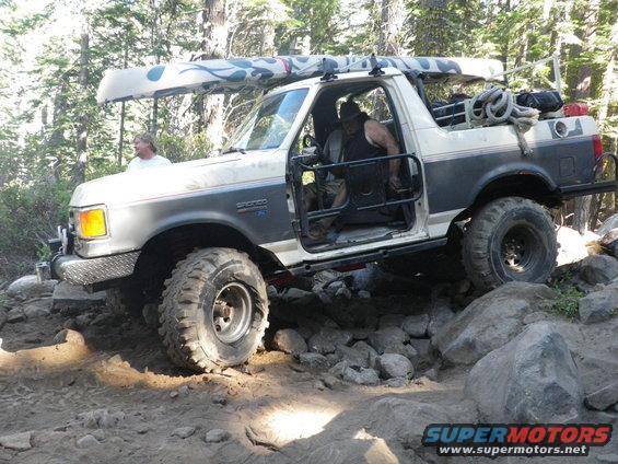 Ford Bronco with canoe on roof navigating rocky terrain