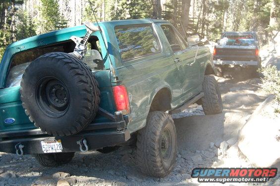 Green Ford Bronco on a rocky trail, another truck behind it