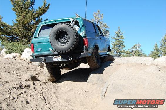 Green 1993 Ford Bronco off-roading on rocks