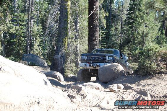 Black pickup truck navigating a rocky, wooded trail