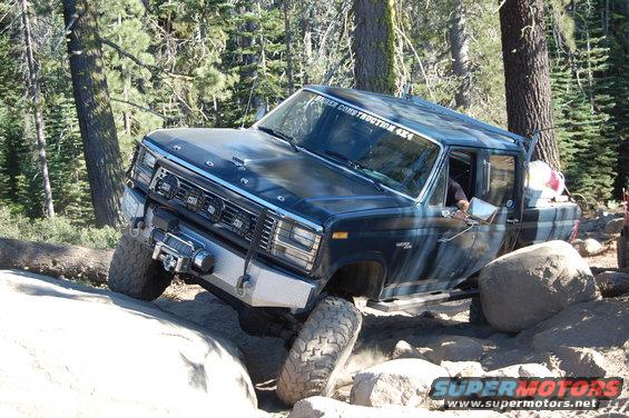 Dark blue Ford F-Series truck navigating a rocky trail, tires angled on boulders