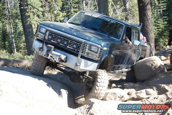 Dark blue pickup truck with winch and off-road lights navigating rocky terrain