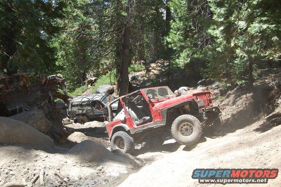1993 Jeep Wrangler and another off-road vehicle navigating a rocky trail in a wooded area