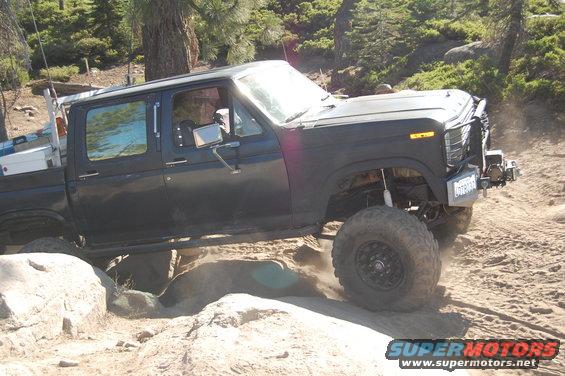 Black pickup truck with lifted suspension and off-road tires navigating rocky terrain