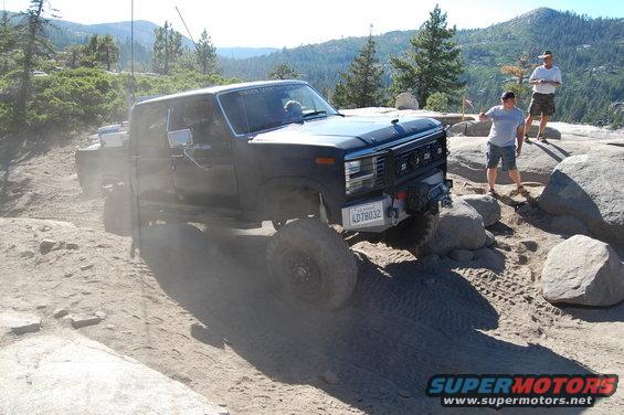 Black Ford F-Series pickup truck with off-road tires navigating rocky terrain. License plate reads 4D78032