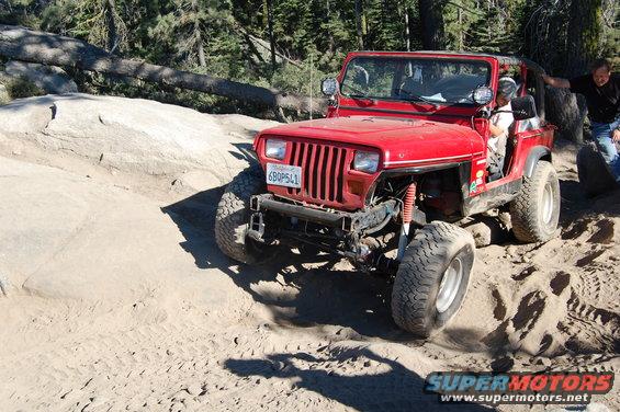 Red 1993 Jeep Wrangler on a dirt trail, front 3/4 view