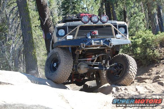 Off-road vehicle with large tires climbing over rocks on a dirt trail