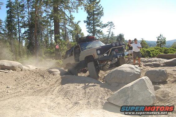 Tan SUV with off-road modifications navigating a rocky, dusty trail
