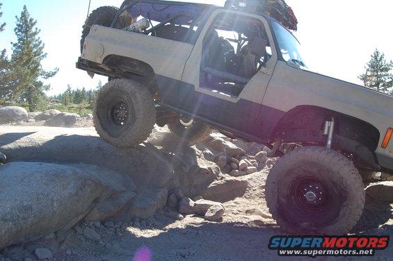 Off-road vehicle with large tires climbing over rocks