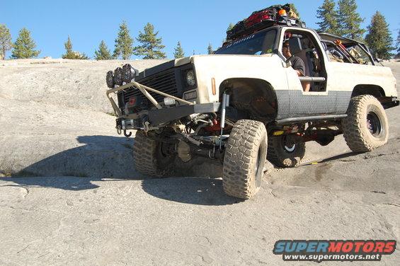 Off-road SUV with large tires and roof rack on rocky terrain