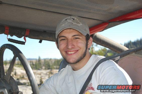 Man wearing a baseball cap inside a vehicle, with a steering wheel visible