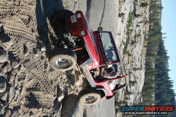 Red 1993 Jeep Wrangler off-roading on a rocky trail