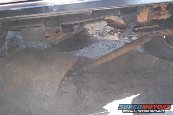 Undercarriage view showing suspension components and a large rock near the tire
