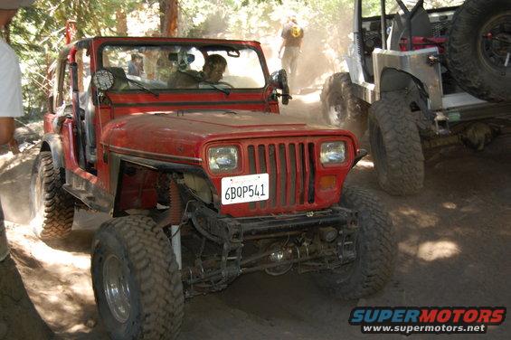 Red 1993 Jeep Wrangler with a license plate reading 6BQP541 on a dusty trail