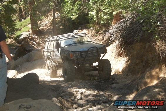 Off-road vehicle with roll cage navigating a rocky trail