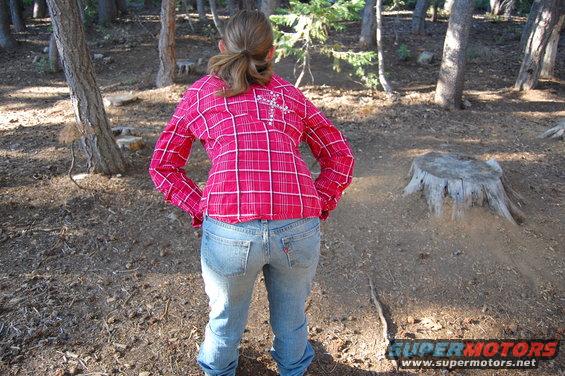 Person from behind in a forest, wearing a pink plaid shirt and jeans