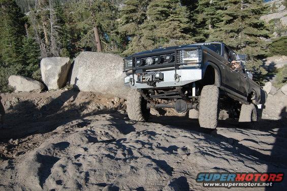 Black pickup truck with large tires and winch on a rocky trail