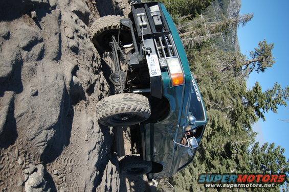 Green off-road vehicle on rocky terrain, front 3/4 view. License plate 5TPM 28
