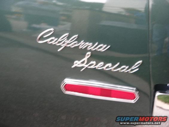 Close-up of 'California Special' script emblem and a red reflector on a dark green car