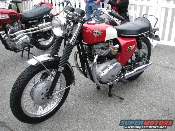 Red and white BSA motorcycle parked next to a red Triumph motorcycle
