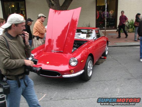 guy with camera next to red vintage sports car with hood up