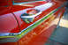 1959 Ford Ranchero - The shiny chrome door handle and trim on a red classic car reflect the surrounding environment.