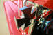1959 Ford Ranchero - A close-up of a chrome and black cross emblem on the exterior of a red vehicle, with a glimpse of the steering wheel and dashboard inside.