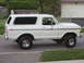 1978 Ford Bronco - A white 1978 Ford Bronco is shown from the side, parked on a street with a garage in the background.