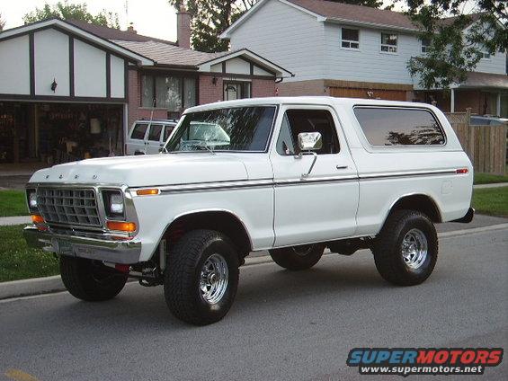 White Ford Bronco parked on street, front 3/4 view. Houses in background