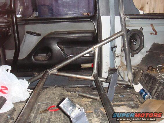 Interior view of a vehicle with a custom roll cage installed. Door panel and speaker visible