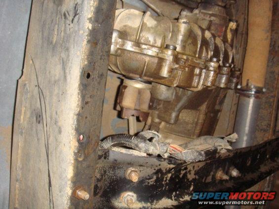 Underside of a vehicle showing the transmission and frame. Some wiring is visible