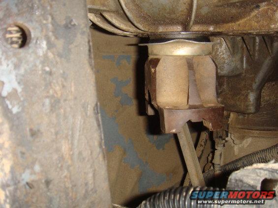 Close-up of a rusty engine mount with rubber dampening, showing dirt and peeling paint