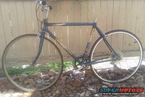 Blue road bicycle with yellow accents on the frame, parked outdoors