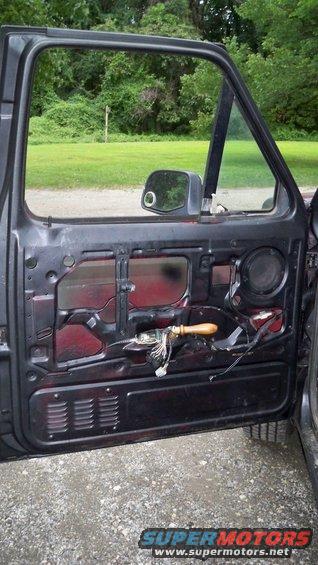 Open car door interior showing exposed wiring and speaker grille
