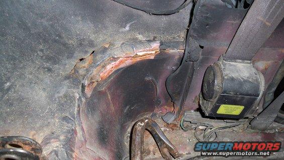rusted metal and seatbelt mechanism inside a vehicle