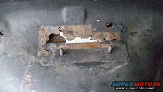 rusted metal bracket with two bolts, showing significant corrosion and damage