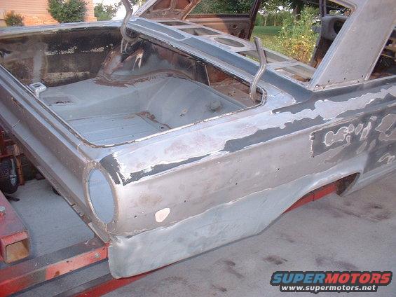 Car body being worked on, showing the trunk area and rear quarter panels. It's stripped down and appears to be undergoing restoration
