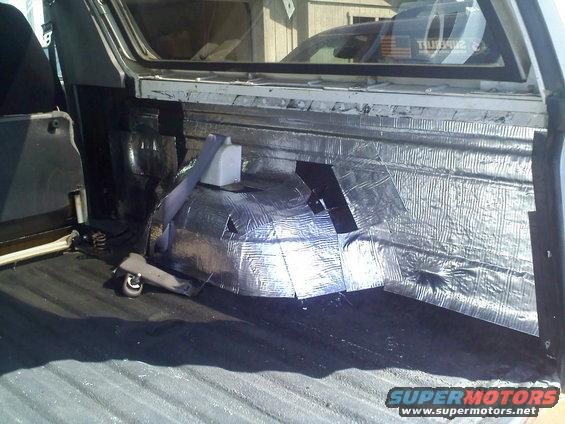 Rear interior of a vehicle with soundproofing material applied to the walls and floor