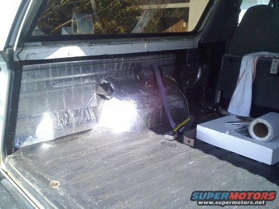 Vehicle interior cargo area with sound deadening material on the wall and a roll of material on the floor