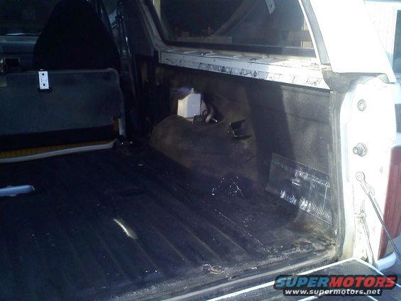 Back cargo area of an SUV, looks like the carpet was removed and it's dirty