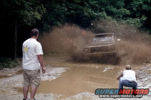 1979 Ford Bronco II driving through a muddy puddle, kicking up water