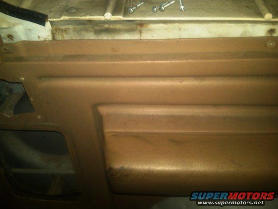 Interior door panel with horizontal ridges and a cutout. Screws are visible on top
