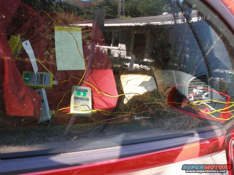 Interior of a red car with two yellow temperature loggers and a notepad on the passenger seat